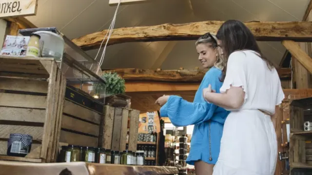 Two women browsing items in a rustic market setting.