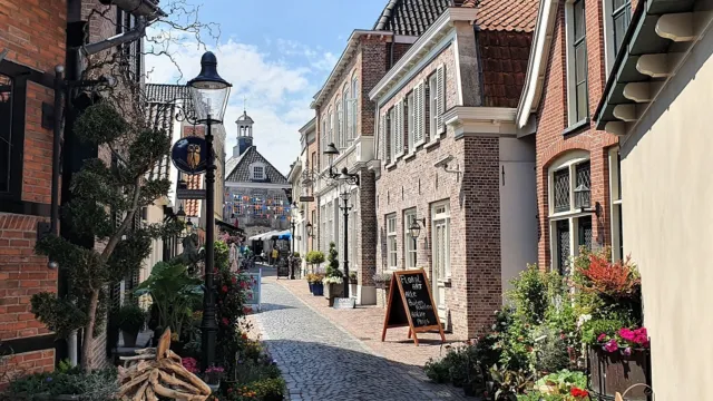 Narrow cobblestone street lined with quaint brick buildings under a clear blue sky.