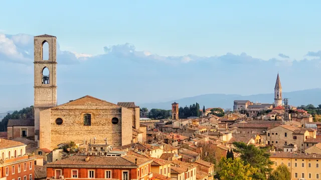 Rooftop view of a historic European city with bell tower and distant hills.