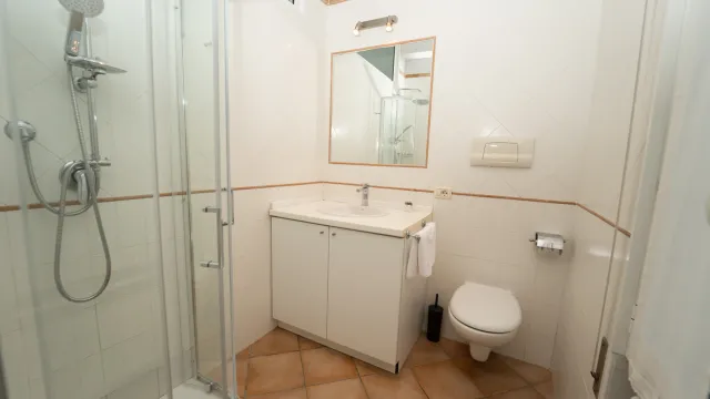 Compact bathroom with a glass shower, sink, and toilet.