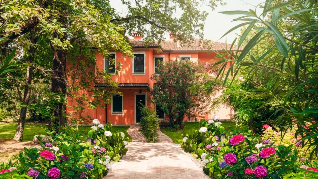 Two-story house with pink flowers and lush green garden.
