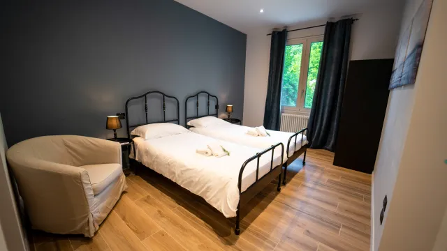 Two twin beds in a modern room with wood floors and a window.