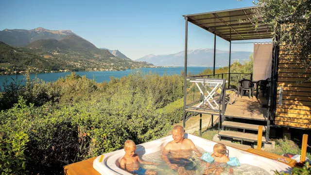 Family enjoying a jacuzzi with a scenic lake and mountain backdrop.
