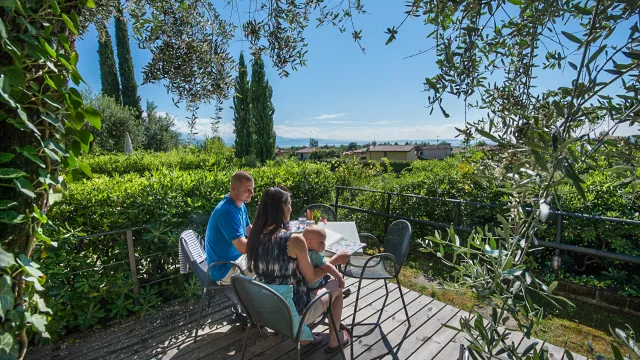 Couple dining on a leafy terrace, scenic countryside view.