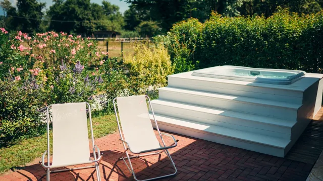Two lounge chairs and a jacuzzi in a garden with flowers.
