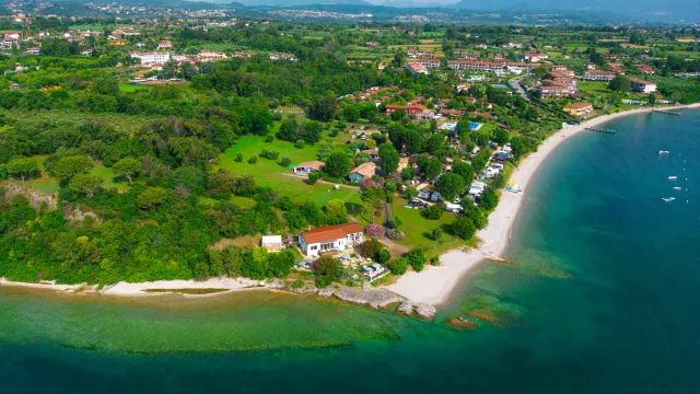 Aerial view of a coastal village with green fields and sandy beaches.