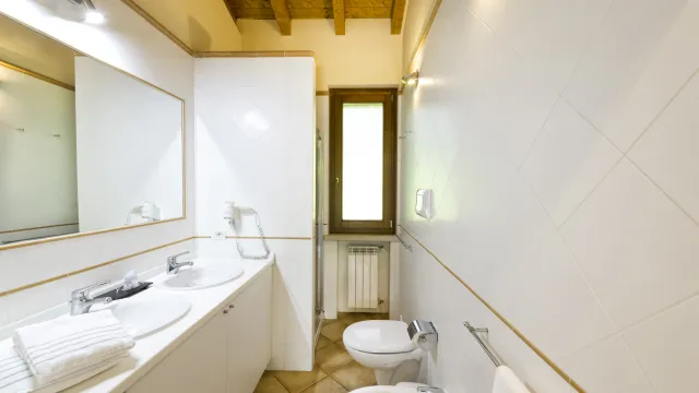 Modern bathroom with two sinks, a bidet, and a window.