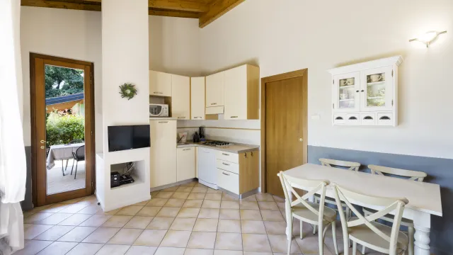 Modern kitchen with white cabinets, dining table, and large window.