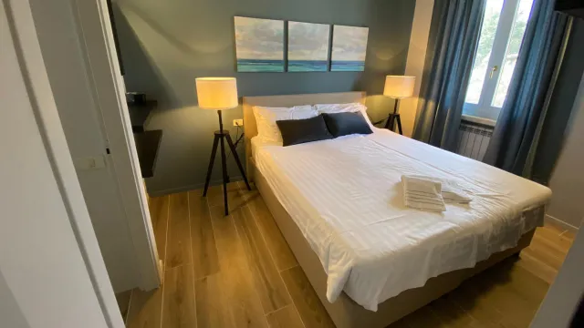 Cozy bedroom with a double bed, lamps, and artwork above.