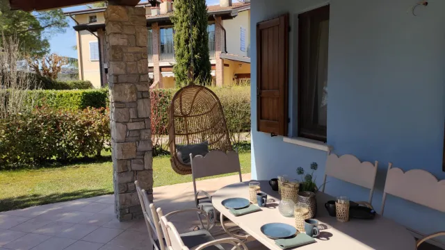 Outdoor patio with a set table and hanging chair, blue walls, and garden view.