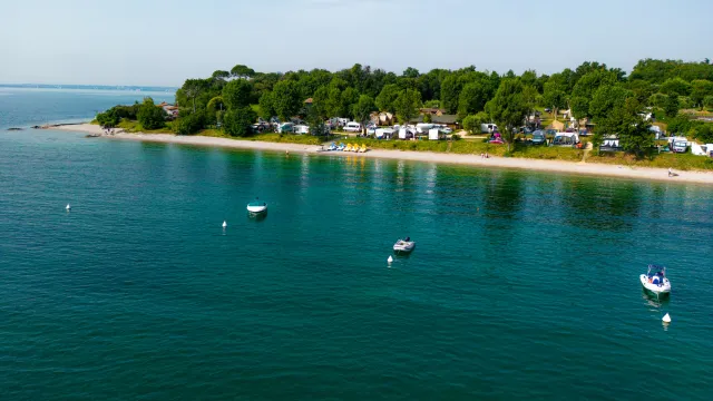 Coastal campsite with calm waters and several anchored boats.