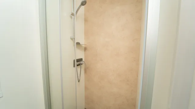 Modern shower with beige tiles and chrome fixtures.