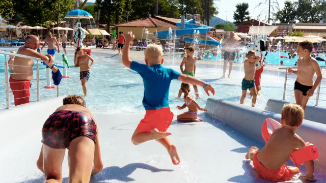 Children playing and splashing in a sunny water park.