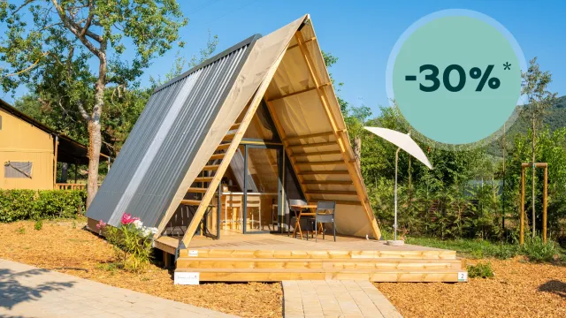 A-frame cabin with wooden deck under a clear blue sky.