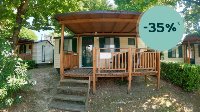 Wooden cabin with a porch under green trees, discount badge "-35%".