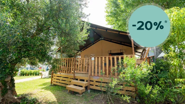 Cozy wooden cabin with a front porch surrounded by greenery, discount tag displayed.