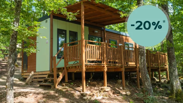 Wooden cabin surrounded by trees, sunny day, discount indicated.