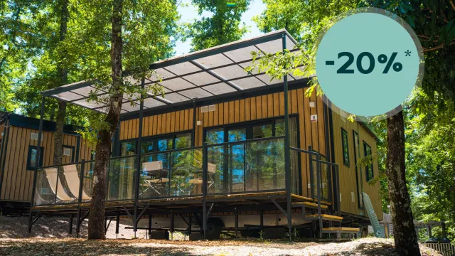 Modern cabin with large windows, surrounded by trees.