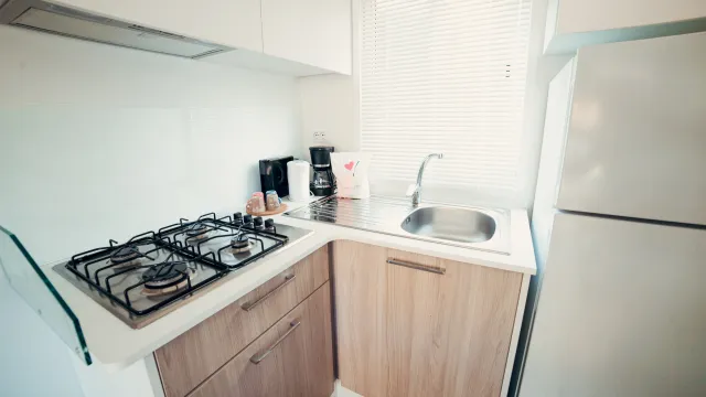 Compact kitchen with stove, sink, and white refrigerator.