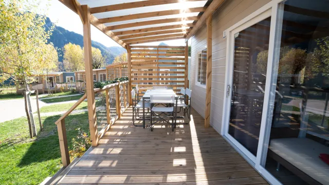 Wooden patio with dining table, chairs, and mountain view.
