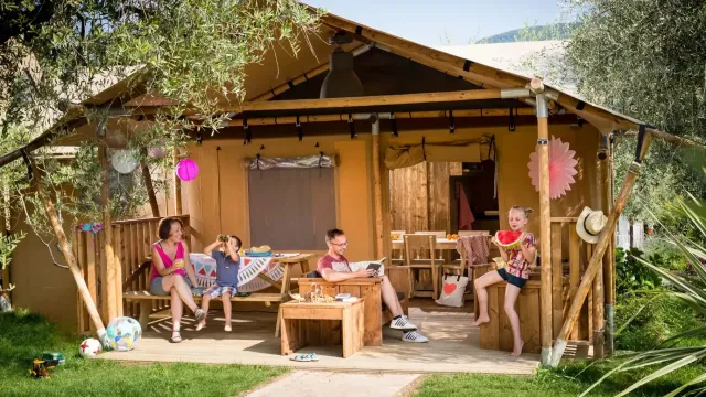 Family relaxing at a wooden campsite cabin with colorful decorations.