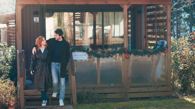 Couple smiling outside a wooden building decorated with garlands.