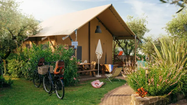 Cozy canvas tent surrounded by lush greenery and a bicycle parked nearby.