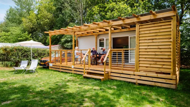 A spacious cottage with a family sitting in the veranda and an open green space around