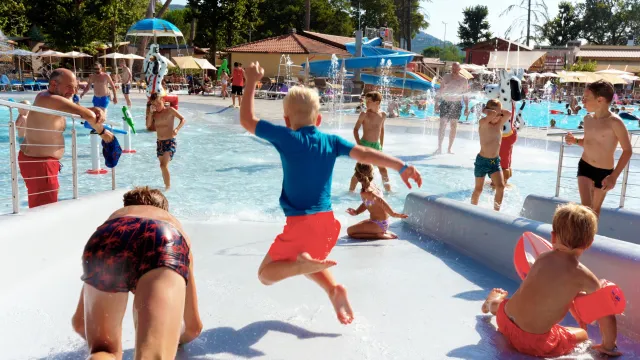 Children using a pool slide and playing in the pool area