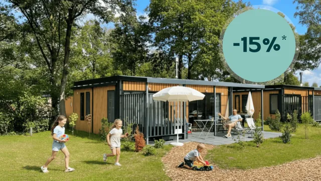 Children playing on grass near a modern cabin under a sunny sky.