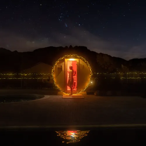 Red-lit phone booth in a starry night landscape, surrounded by mountains.
