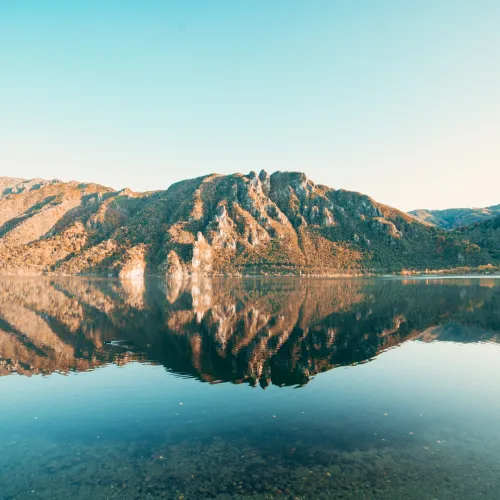 Mountain reflected in a serene lake under a clear blue sky.