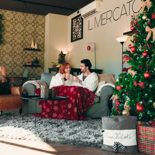 Cozy couple by Christmas tree in warm, festive living room.