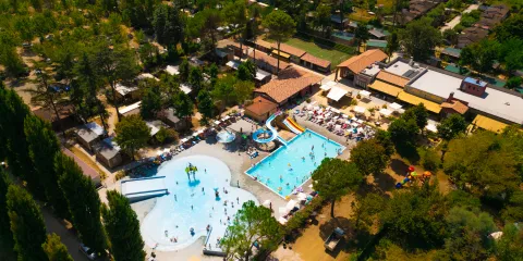 Aerial view of a resort with two pools and surrounding greenery.