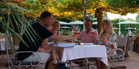 Family dining outdoors, under string lights, enjoying drinks and conversation.