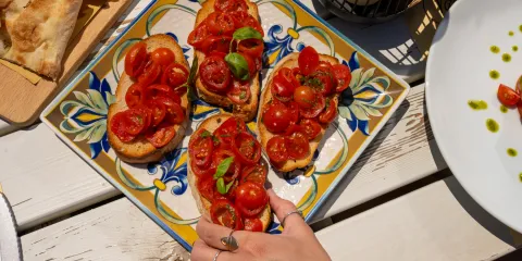 Bruschetta with cherry tomatoes on a decorative plate, white table setting.