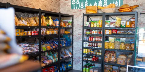 Grocery shelves with packaged foods in a store with brick walls.