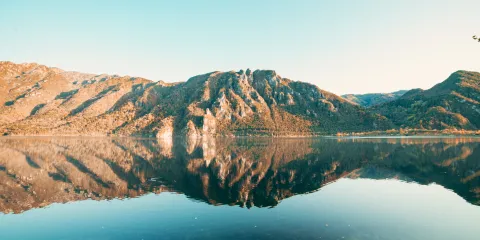 Mountain reflected in a serene lake under a clear blue sky.