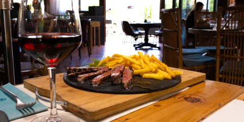 Steak and fries with red wine on a restaurant table.