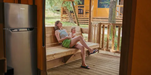 Mother and child relaxing on a porch swing at a cabin.