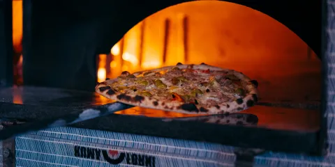 Pizza baking in a glowing wood-fired oven.