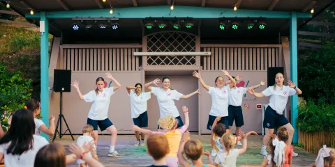 Children dance along with performers on an outdoor stage.