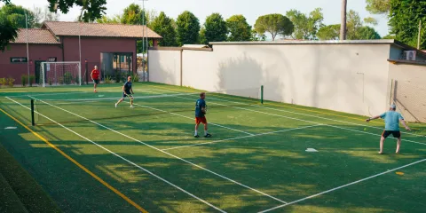 Tennis match on a green court with three players under a clear sky.