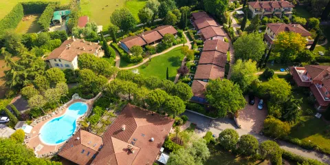 Aerial view of a residential area with greenery and a pool.