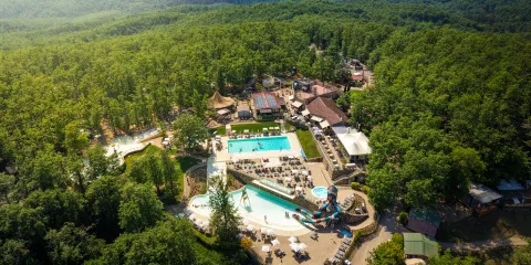 Aerial view of a water park surrounded by dense forest and mountains.