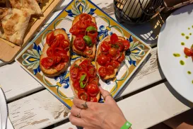 Bruschetta with cherry tomatoes on a decorative plate, white table setting.