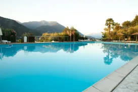 Outdoor pool with mountains and trees in the background, under a clear sky.