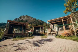 Cabins with wooden porches, mountain backdrop, clear sky.