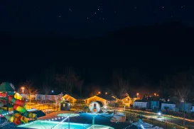 Nighttime playground and pool area, festive lights, starry sky.