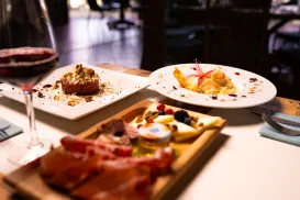 Charcuterie board and desserts on a dining table with a glass of red wine.